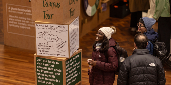 Student smiling next to block signage with campus suggestions written on them